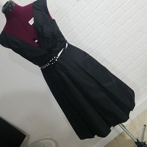 Black dress. V neck with folds. Fitted top. Large plaid from waist/bell shape.